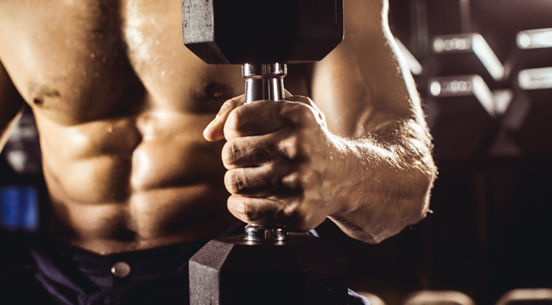 Muscular man holding a dumbbell and performing grip strength exercises and demonstrating curling mistakes