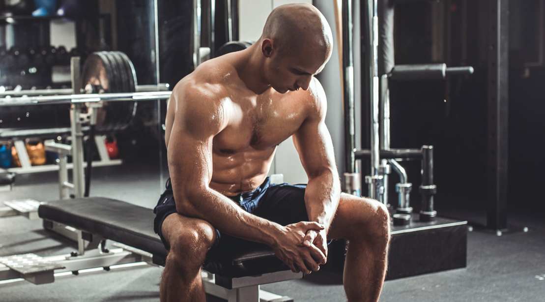 Bald-Sweaty-Man-Resting-Barbell-Bench