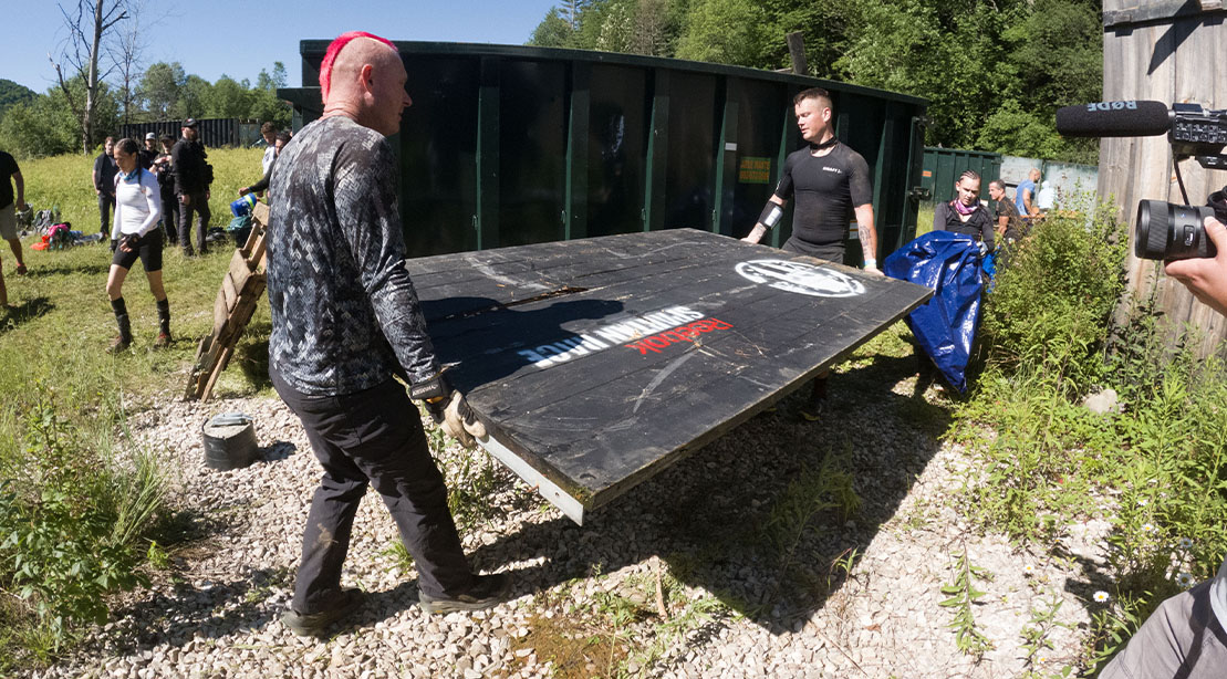 Competitors at the 2024 Spartan Death Race loading plywood with the Spartan Death Race Logo painted on it