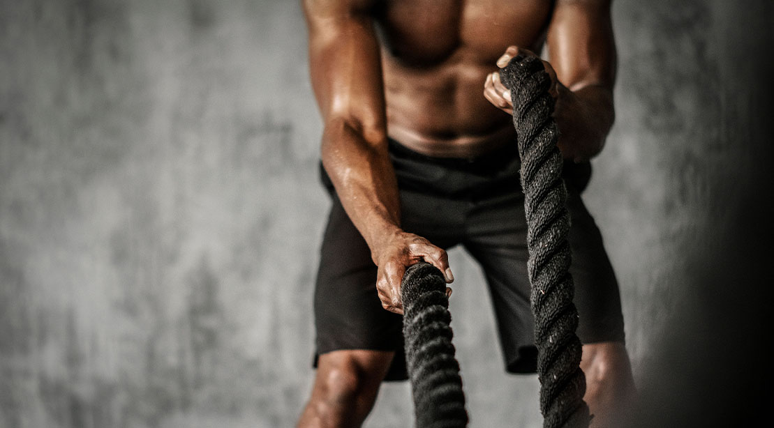 Man performing a High intensity training workout using battle ropes and high lactate training principles