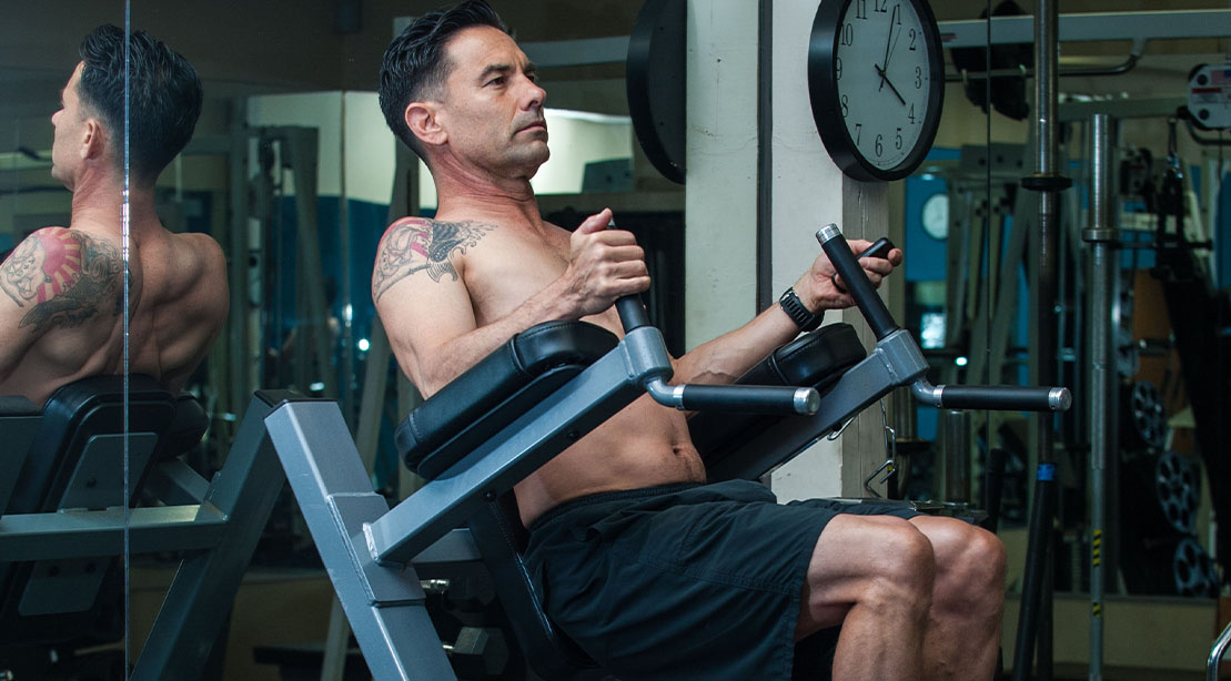 Muscular fit man with tattoos working out his abs with a captain's chair exercise and workout